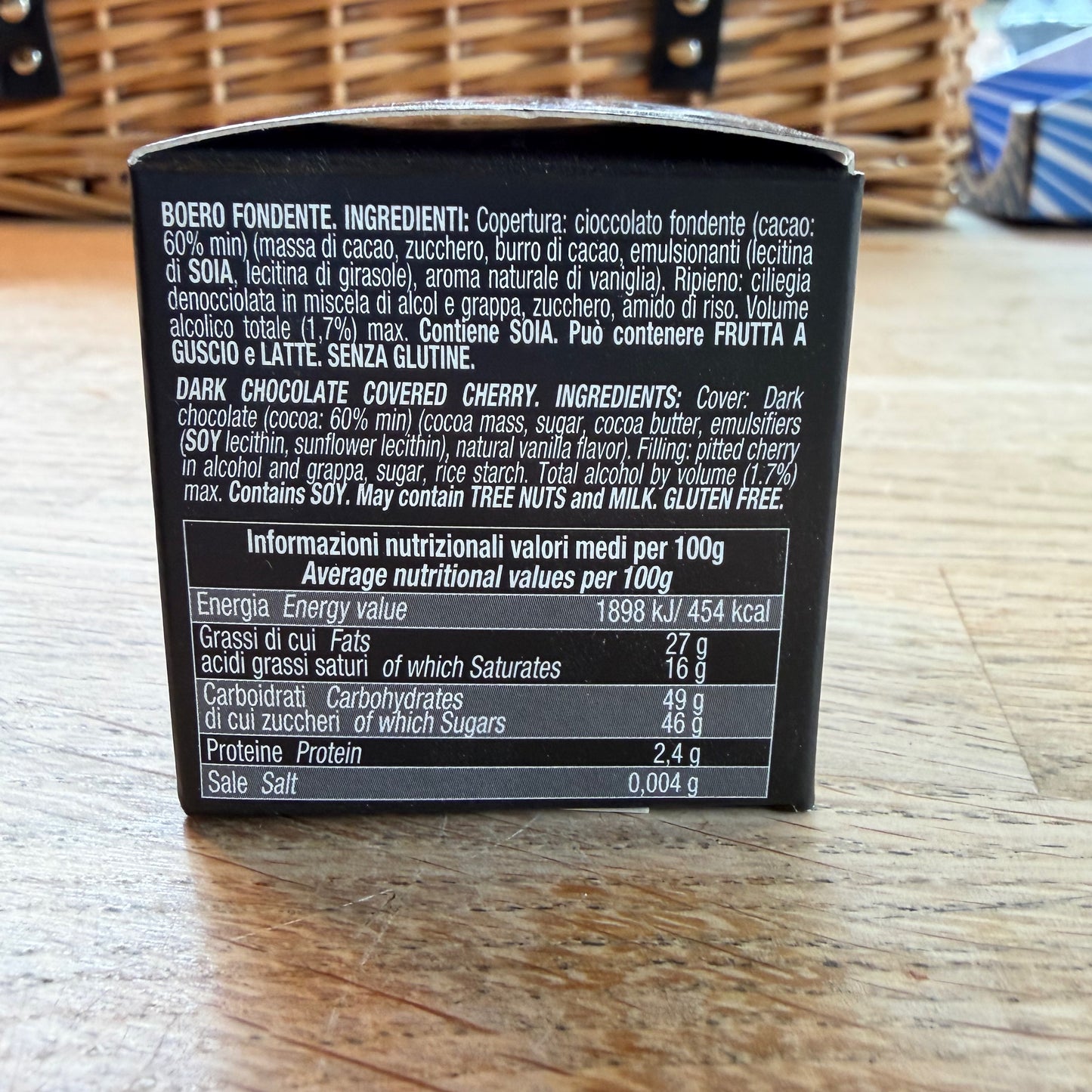 Back of a dark chocolate covered cherry packaging with ingredient list and nutritional information on a wooden surface.