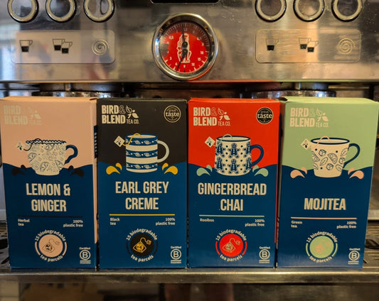 Four Bird Blend tea boxes displayed on a metal coffee machine shelf: Lemon & Ginger, Earl Grey Creme, Gingerbread Chai, and Mojtea.
