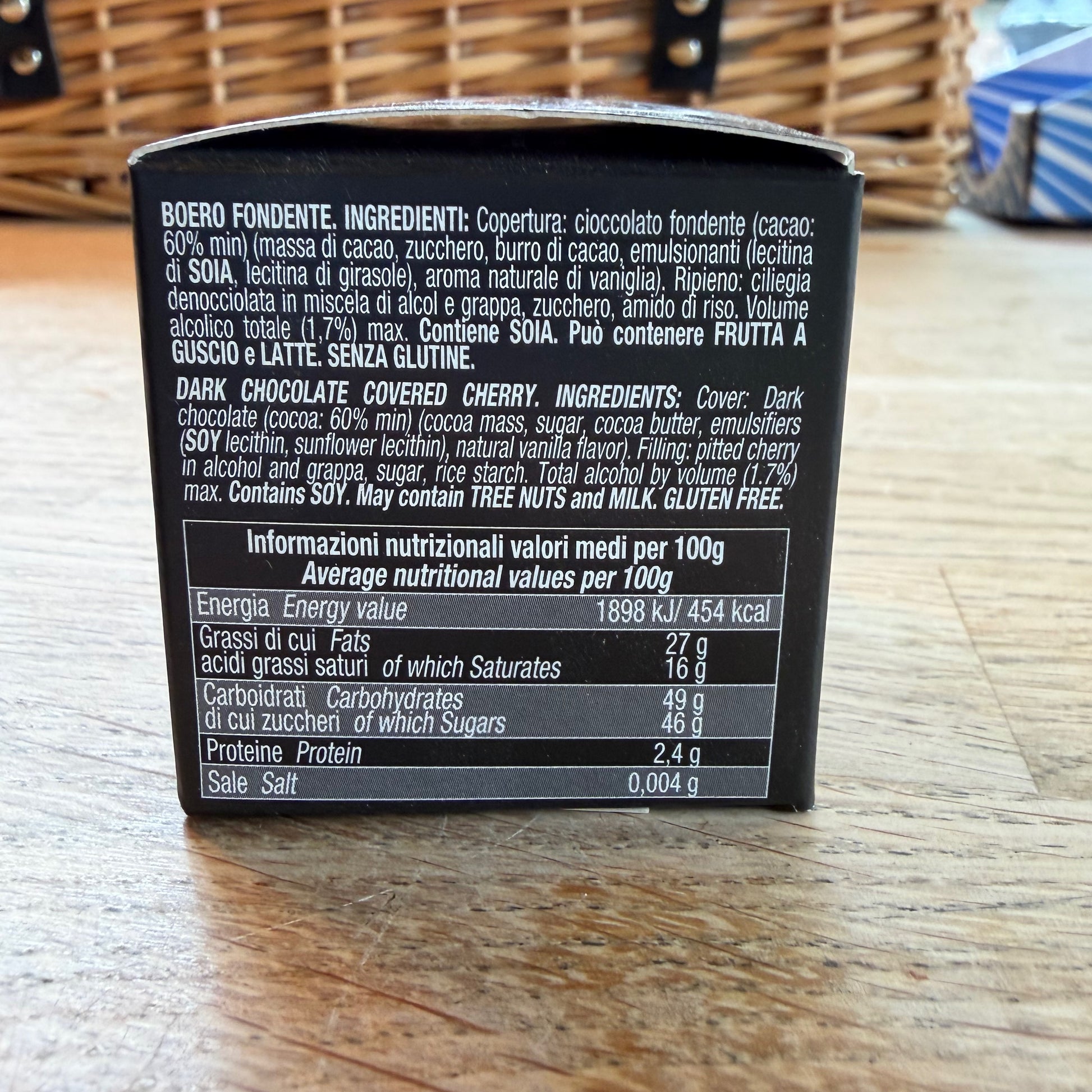 Back of a dark chocolate covered cherry packaging with ingredient list and nutritional information on a wooden surface.
