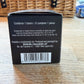 Back of a black packaging box with text and a barcode on a wooden surface.
