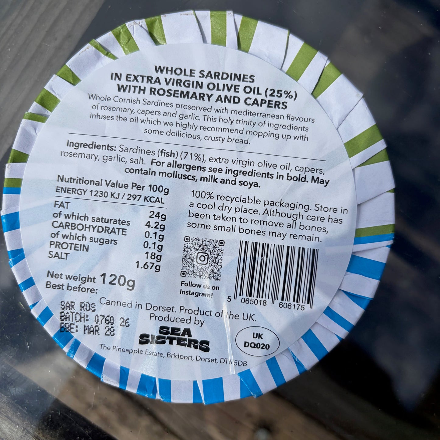 Back of a sardine can label with text and barcode on a glass surface