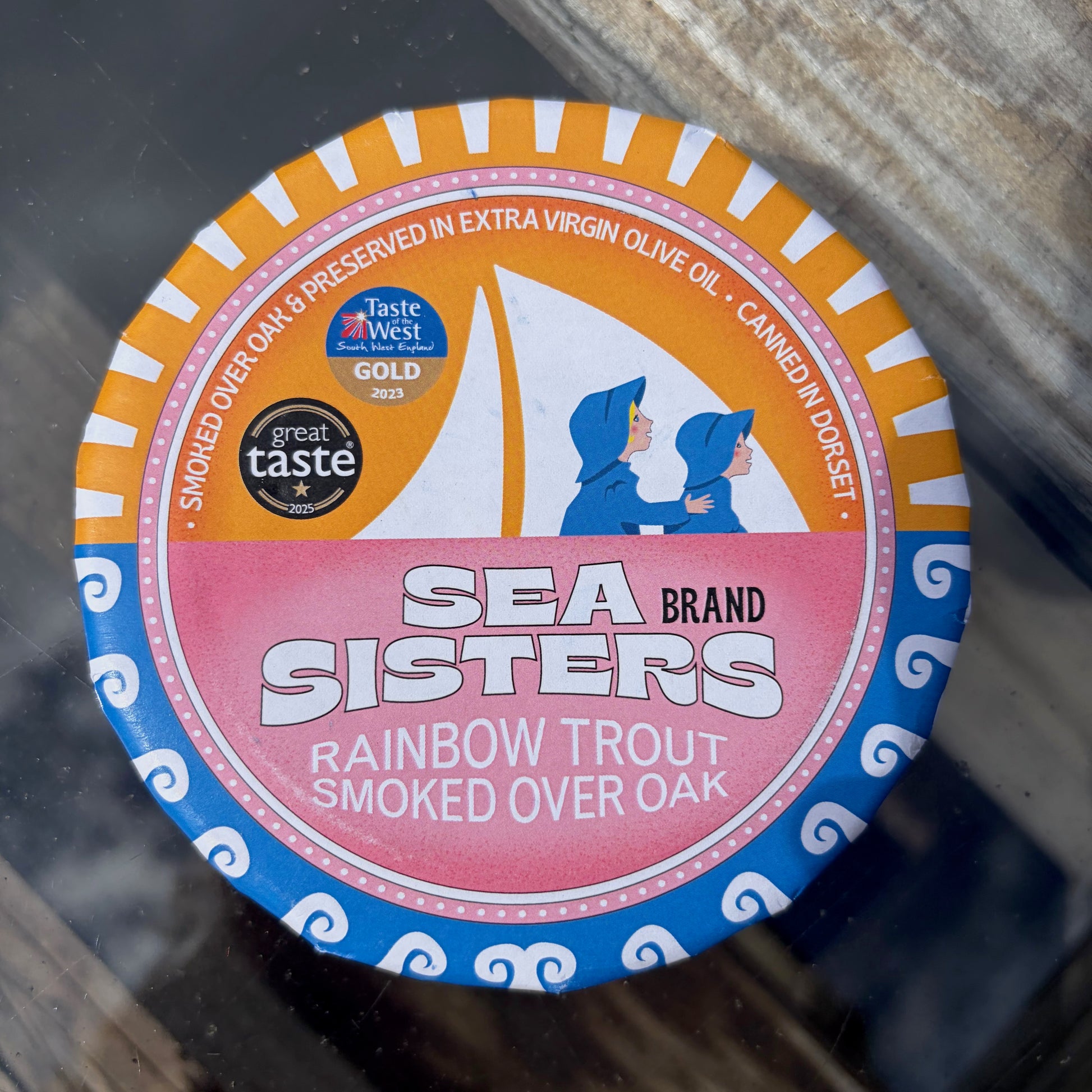 Sea Sisters rainbow trout smoked over oak tin on a glass surface