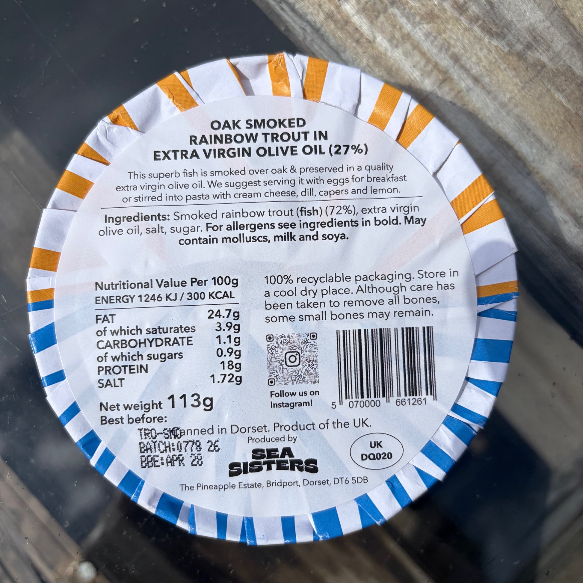 Label of oak smoked rainbow trout in extra virgin olive oil on a glass surface